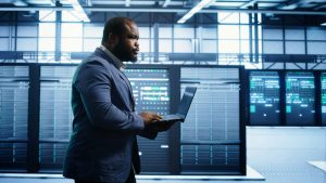 Man walking in server room, monitoring server infrastructure