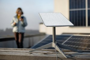 Starlink satellite dish on roof of residential building and woman on background