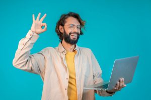 Portrait of a man holding laptop computer and celebrating success isolated over blue background