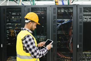 Young technician man working with tablet inside big data center room