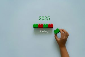 Loading new year 2024 to 2025 with child hand putting plastic block in progress bar.