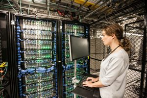 Caucasian woman technician doing diagnostic tests on computer servers in a server farm.