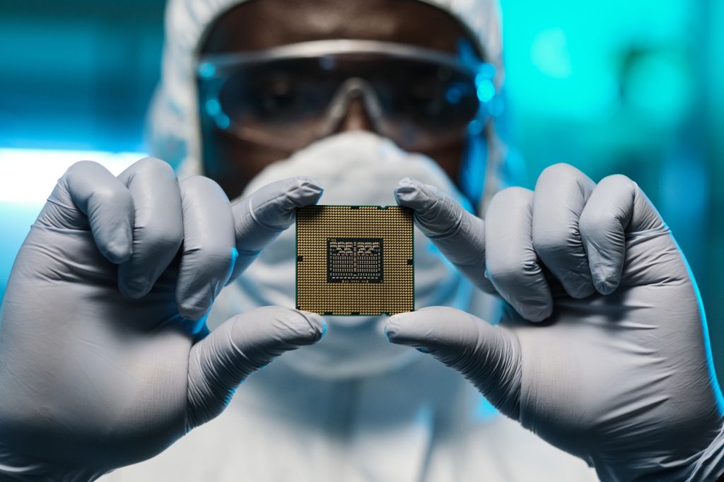 Gloved hands of African man in protective coveralls showing you microchip