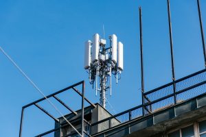 Mobile network cell tower on top of building in city.