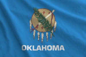 Oklahoma US state flag depicted on folded wavy fabric of old cloth